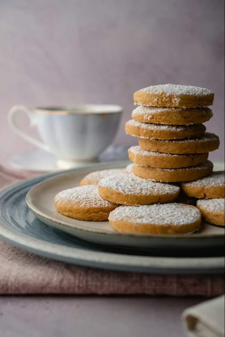 Pile de sablés dorés saupoudrés de sucre, sur une assiette de grès